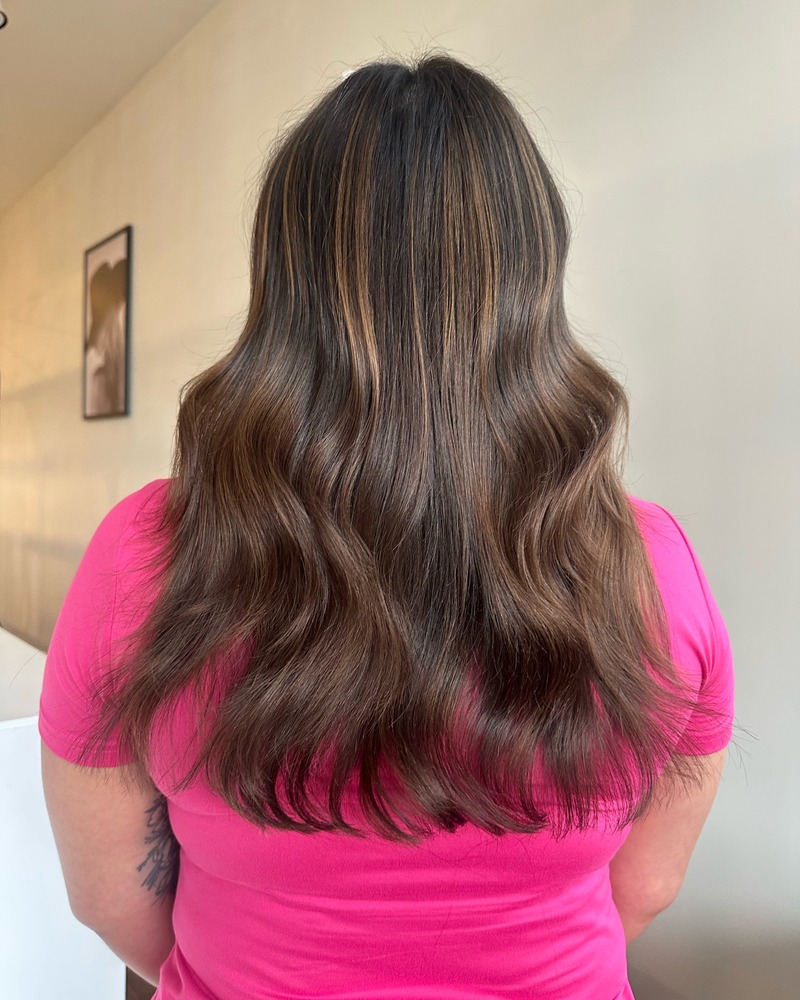 Lived-in dimensional brunette color styled in soft waves at Rise Above Beauty Lounge in Colorado Springs